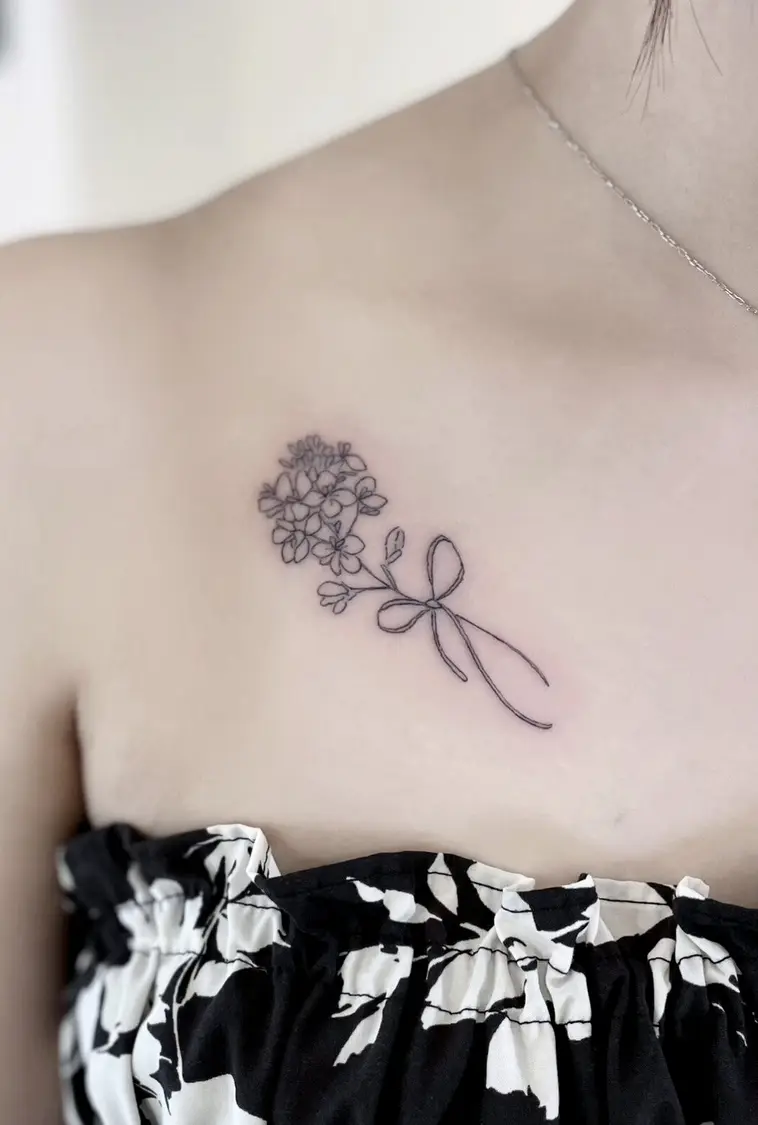 鎖骨下の花束とリボンのファインラインタトゥー
