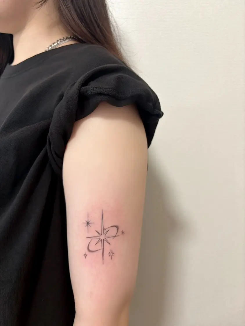 女性の二の腕に施された、星とキラキラをモチーフにしたラインワークタトゥー