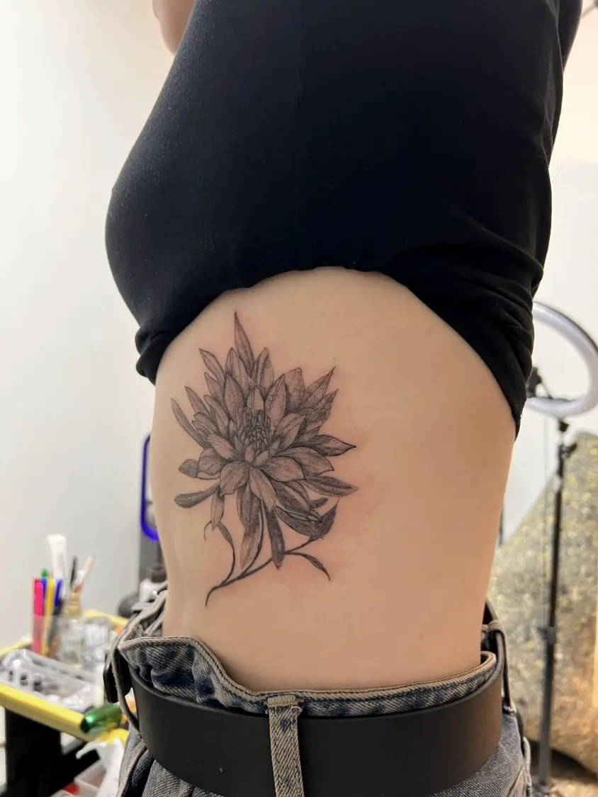 女性の脇腹に彫られた大きな花のタトゥー